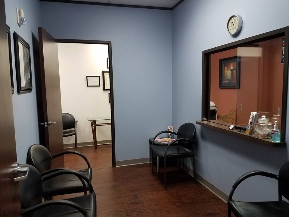 The entryway of Synergy Chiropractic of Houston. The waiting room leads to the main hallway, while the office assistant's office is to the right behind the glass window.